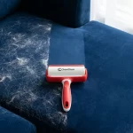 High-angle, close-up shot of a dark blue velvet sofa cushion, one half is visibly covered in white pet hair