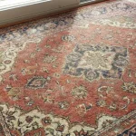 Photo of a vintage carpet in the eastern style with a red-blue color, in the summer The wool is placed on the wooden top of the window, with the cat toy in the corner.