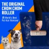 Close-up action shot of a hand removing white pet hair from a blue velvet chair using the limited dog edition ChomChom roller. A cat and dog look surprised in the foreground