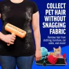 A woman holding the orange roller against a black t-shirt covered in shedding fur, demonstrating how to remove hair from clothing without snagging the fabric.
